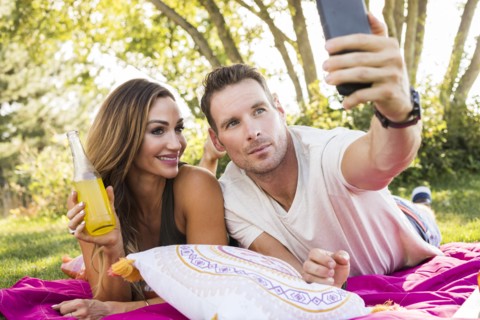 Man taking picture with smart phone at picnic in park