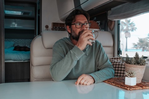 Man sitting in mobile home and drinking tea