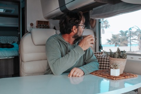 Man sitting in mobile home and drinking tea