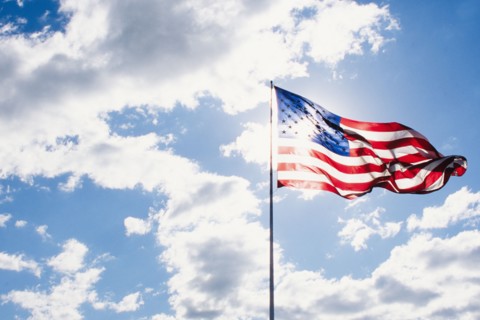 American flag blowing on wind against sky on sunny day