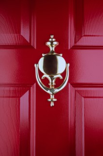 Close-up of old fashioned brass door knocker on red front door