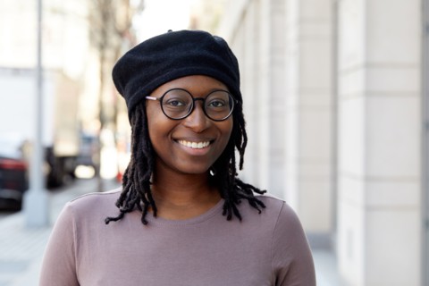 Portrait of smiling woman wearing eyeglasses and beret in city