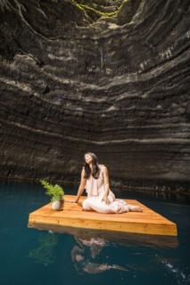Woman sitting on floating dock near rocky coast