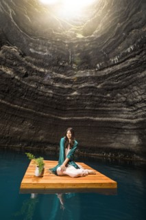 Portrait of woman sitting on floating dock near rocky coast