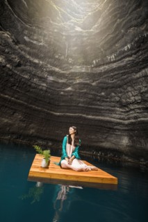 Woman sitting on floating dock near rocky coast