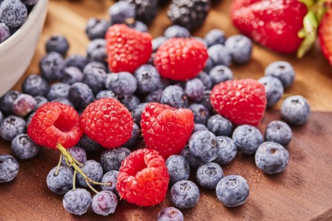 Studio shot of fresh blueberries and raspberries on wooden surface