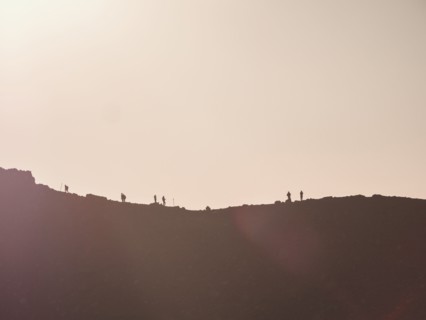 Silhouettes of hikers on mountain ridge at sunset