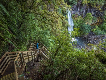 Hiker walking down wooden stairs towards waterfall