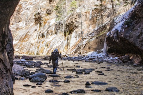 Senior woman crossing stream while hiking in mountains