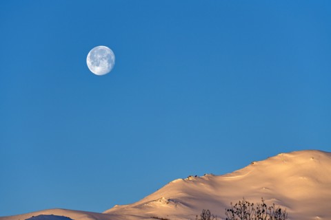 Full moon over snow-covered hills