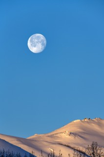 Full moon over snow-covered hills
