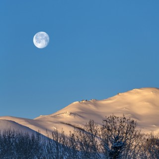 Full moon over snow-covered hills