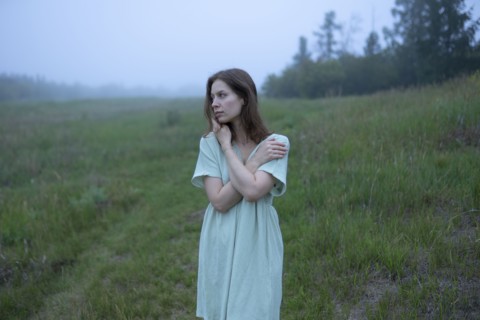 Woman standing in meadow on foggy day