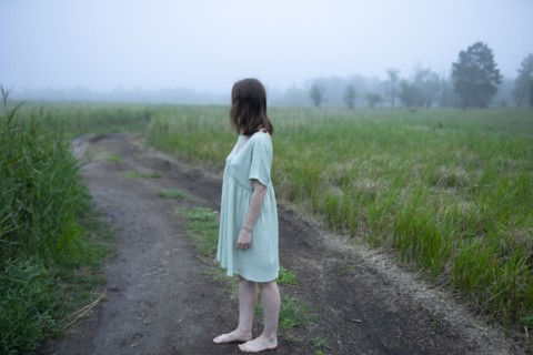 Woman standing on dirt road and looking away
