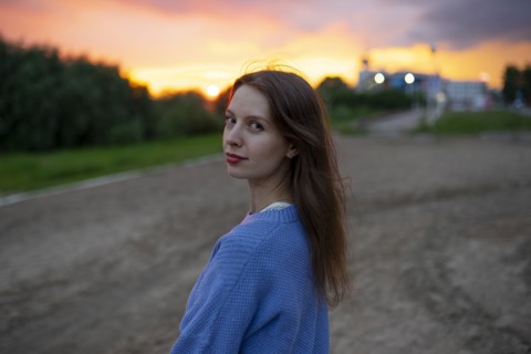 Portrait of beautiful woman standing in field at sunset