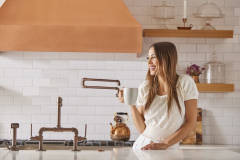 Smiling woman holding mug in kitchen