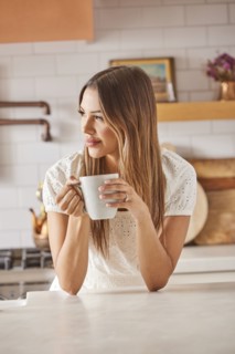 Smiling woman holding mug in kitchen