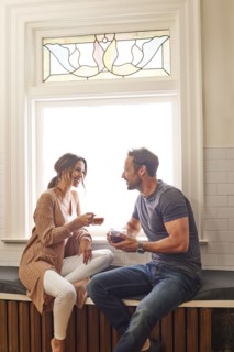 Smiling couple relaxing by window at home