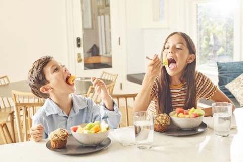 Boy and girl eating breakfast in kitchen