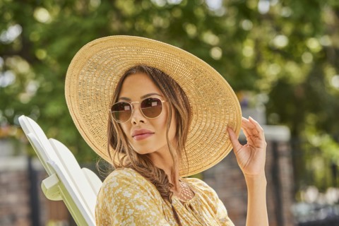 Woman in straw hat and sunglasses relaxing in park