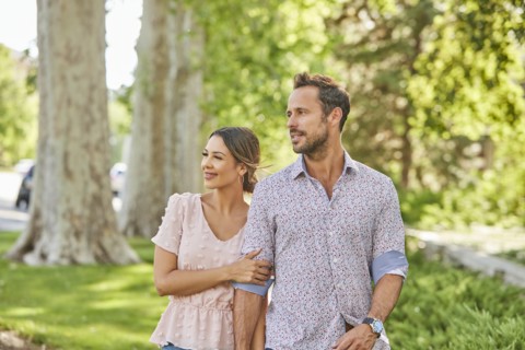 Smiling couple walking on treelined sidewalk
