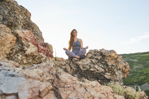 Mid adult woman meditating in mountains