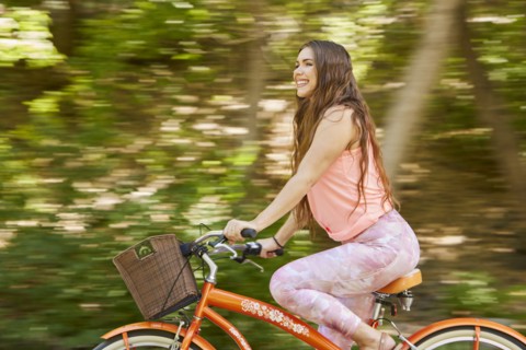 Smiling young woman riding bicycle in park