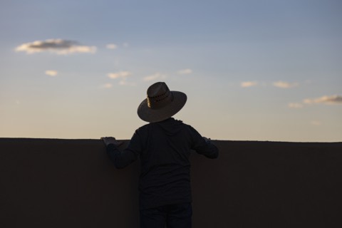 Silhouette in hat looking at sunset