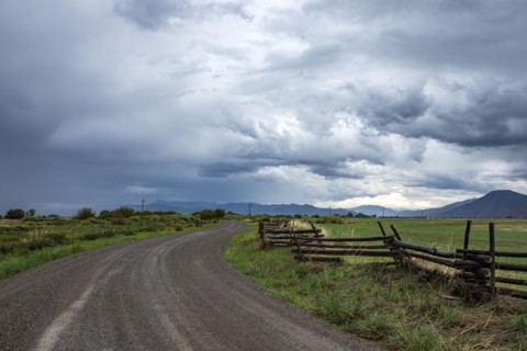 Dramatic clouds above empty road and meadow