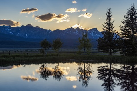 Scenic view of Sawtooth Mountains with pond at sunset