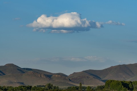 Cloud floating over foothills on sunny day