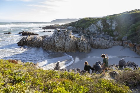 Brother and sister exploring rocky coastline in Voelklip Beach