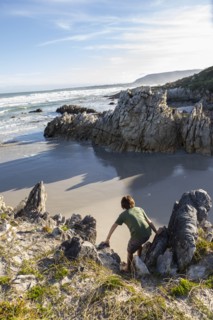 Boy exploring rocky coastline in Voelklip Beach