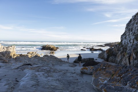 Brother and sister exploring rocky coastline in Voelklip Beach