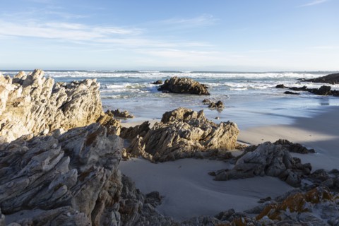 Rocky coastline with Atlantic Ocean in Voelklip Beach on sunny day