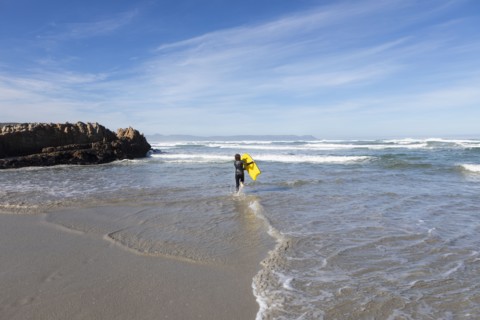 Boy entering Atlantic Ocean with body board in Kammabaai Beach