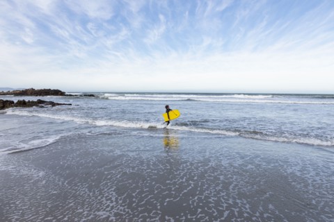 Boy entering Atlantic Ocean with body board