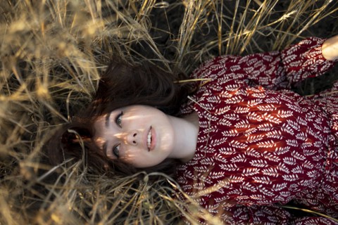 Directly above view of woman lying on cereal plants in field