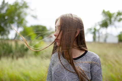 Blonde young woman with tousled hair in field