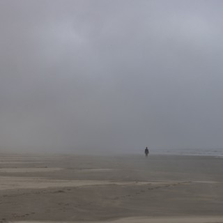 Misty figure walks along beach