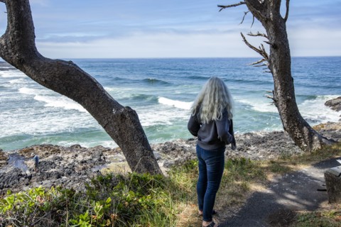 Senior woman looks out to sea on rocky headland