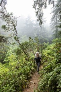 Senior woman hiking on hill with nordic walking poles