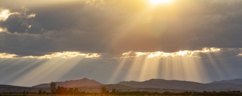 Rays from setting sun shining on fields and hills