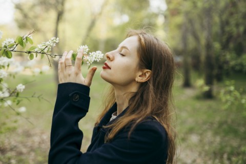 Beautiful woman smelling flower in orchard