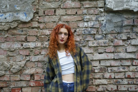 Redhaired woman posing next to old brick house