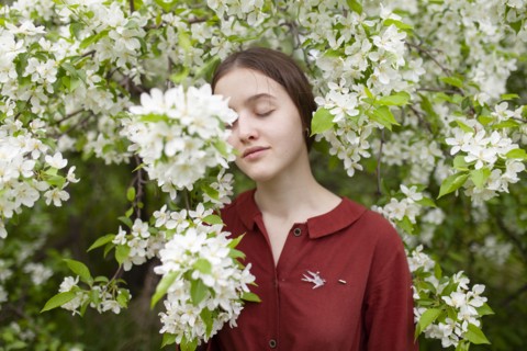 Young woman standing with closed eyes by tree in blossom