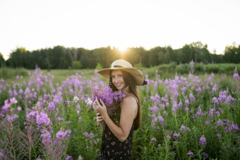 Portrait of smiling woman with flowers on meadow