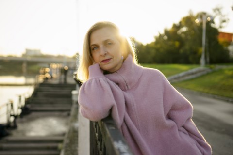 Portrait of serious woman leaning on railing at sunrise
