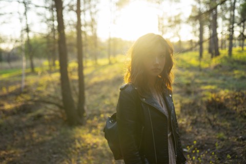 Portrait of woman standing in forest on sunny day