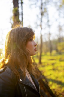 Side view of woman looking at forest on sunny day